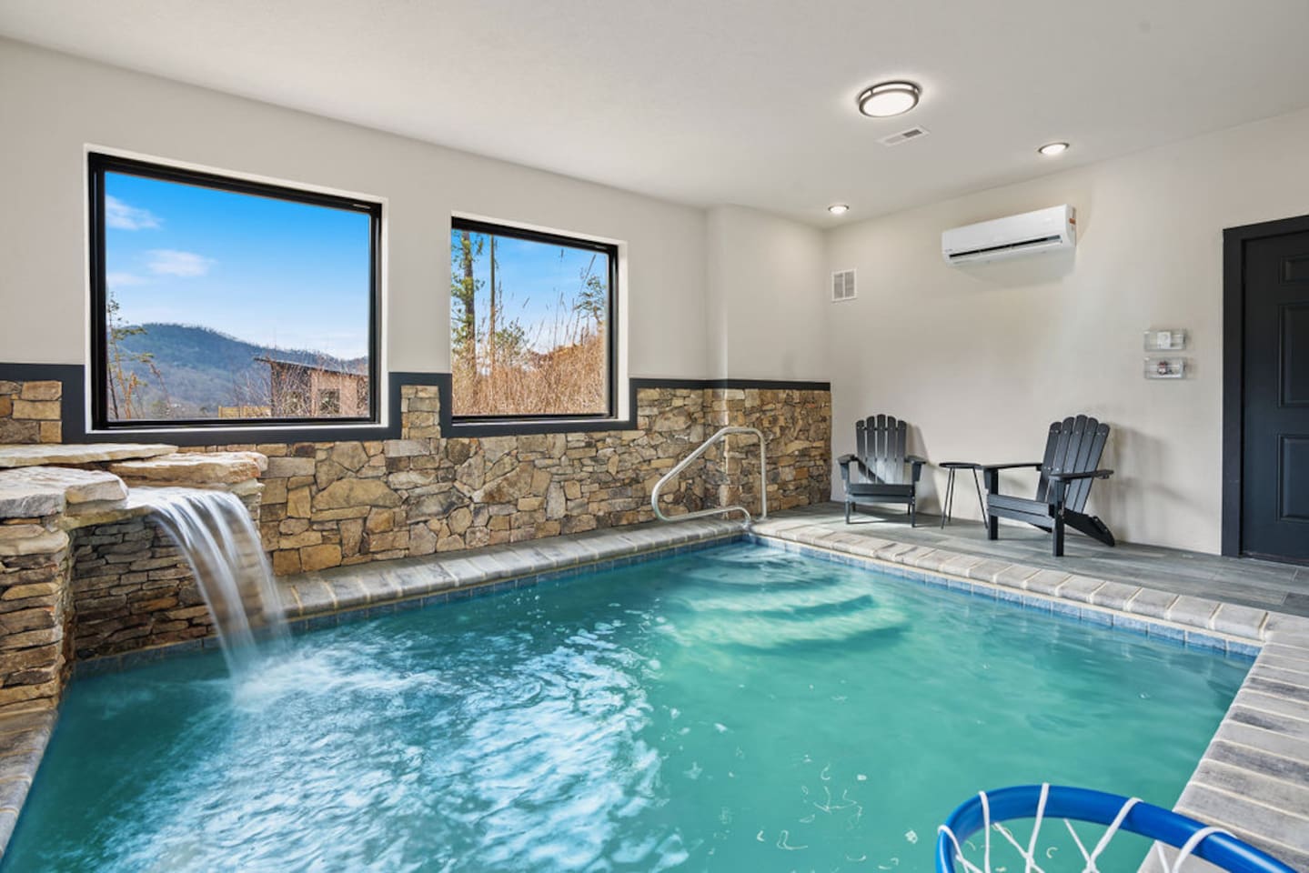 Indoor pool with stone walls, waterfall feature, and mountain views